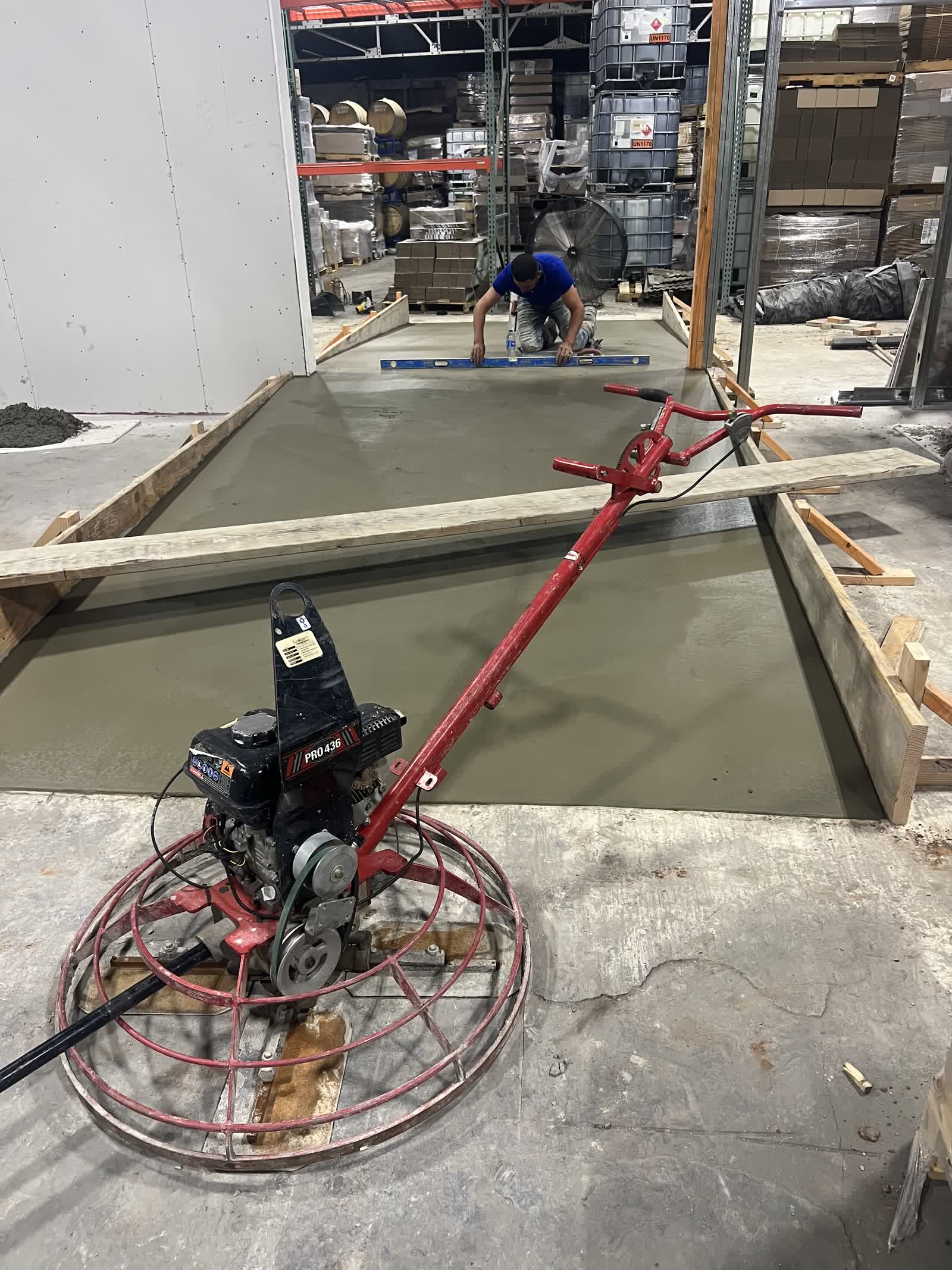 Crew troweling concrete forklift ramp in Guthrie, OK warehouse — forms and fresh pour visible