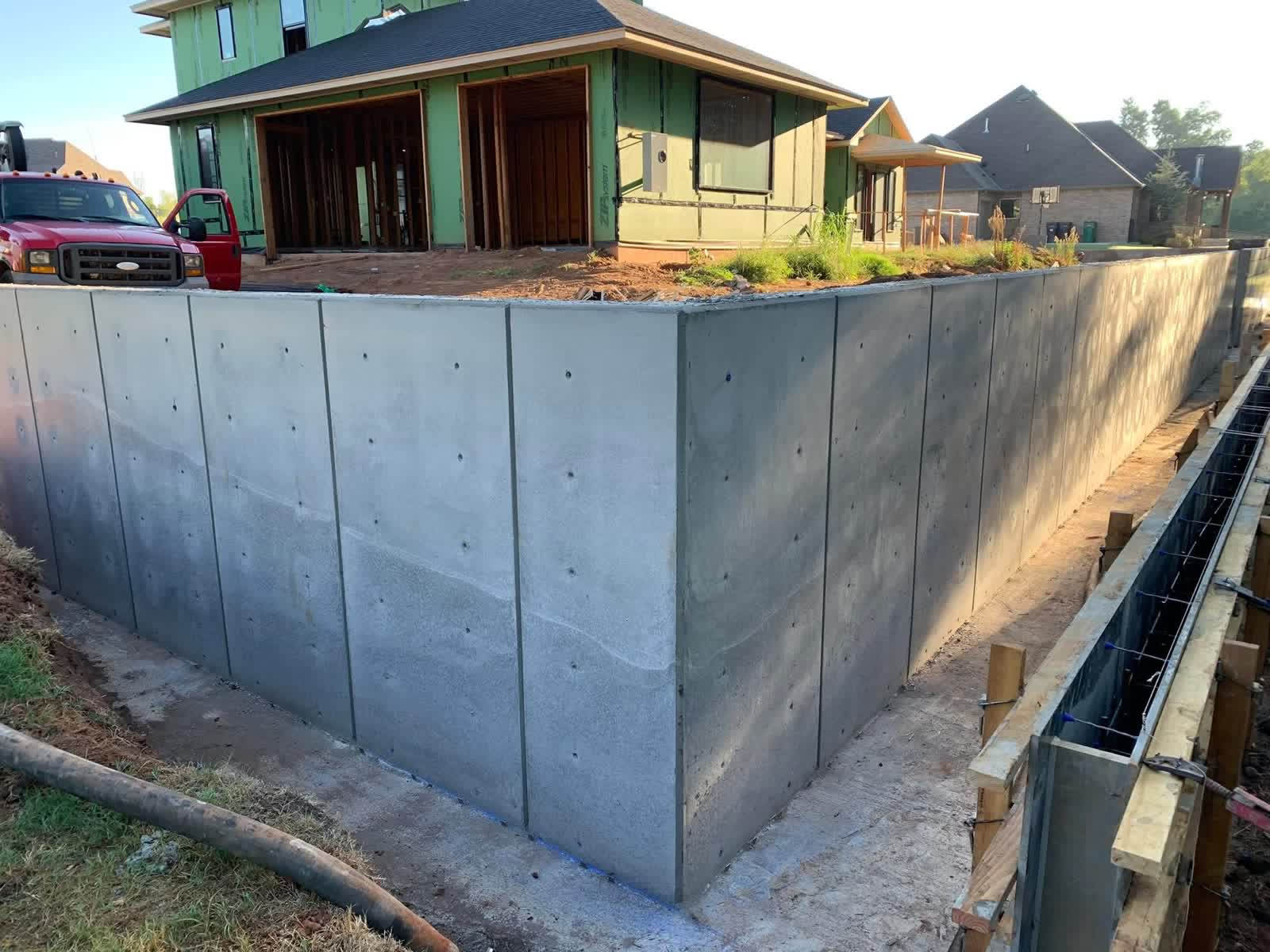 Tall poured concrete retaining wall in Oklahoma City — monolithic structure supporting new residential construction on expansive clay soil