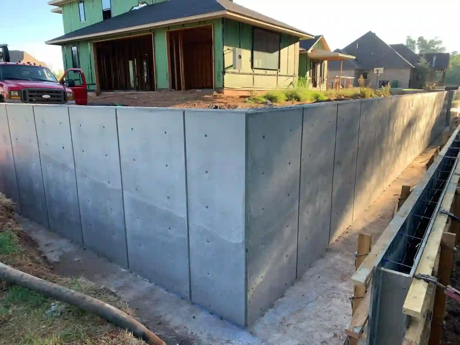 Poured concrete retaining wall with forms stripped beside a new home under construction in Oklahoma City, OK, with the next wall section still formed